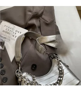 Detail of silver crocodile-pattern shoulder bag with wide leather strap and chunky metal chain
