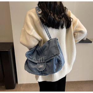 Detailed view of blue denim tote with silver chain strap and metal turn-lock closure
