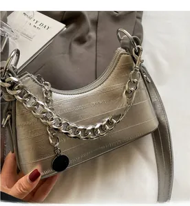 Close-up of silver crescent bag featuring metallic chain and textured horizontal leather