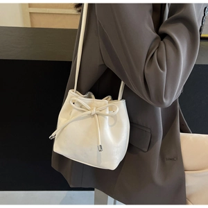 Détail du sac seau blanc cassé avec cuir souple et décoration de nœud élégant