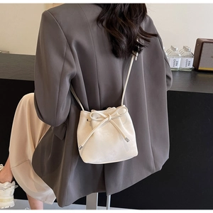 Vue de dos d'un mannequin portant un sac seau en cuir blanc avec cordon et nœud