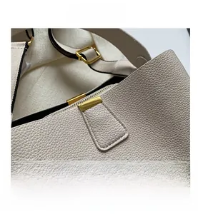 Detailed close-up of cream-white lychee grain leather handbag with gold metal hardware
