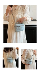 Detailed close-up of light blue quilted vanity bag with chain strap and top handle