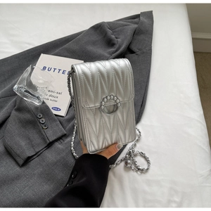 Dettaglio della mini borsa trapuntata argento con chiusura ad anello di perle e catena