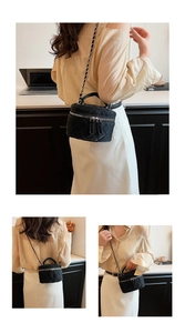 Detail of black quilted vanity bag with silver-tone chain strap and dual zipper closure