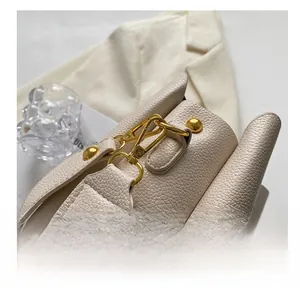 Close-up of cream pebble leather bag showing golden hardware and strap detail