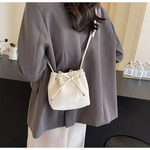 Détail d'un sac seau blanc crème à cordon avec bandoulière vue de côté sur un mannequin
