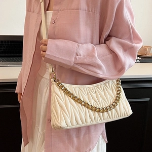 Sac hobo blanc plissé en similicuir avec chaîne dorée porté par un mannequin élégant