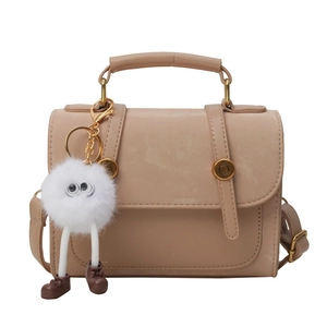 Chic beige PU leather handbag with gold hardware and a cute white fuzzy monster keychain