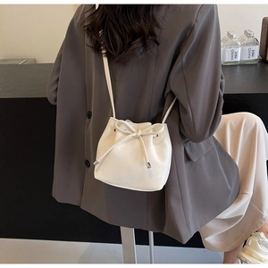 Détail du sac seau crème avec cordon de serrage et bandoulière en cuir porté par un modèle