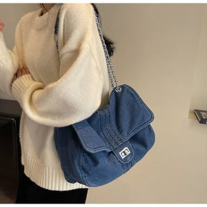 Detailed view of blue denim shoulder bag with silver chain strap and metal turn-lock