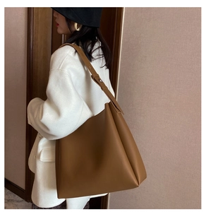 Detailed side view of a large brown leather tote bag with silver rivet strap accents
