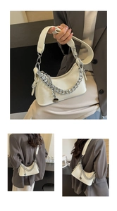 Detail of cream crocodile pattern underarm bag with silver chain and metal charm decoration