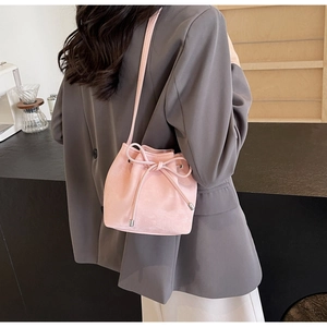 Gros plan d'un sac seau rose à cordon avec un nœud sur un blazer gris élégant