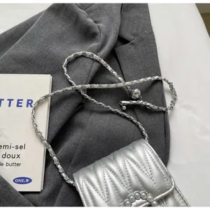 Dettaglio borsa a tracolla argento trapuntata con fibbia di perle e catena argentata