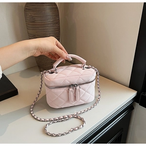 Close-up of pink quilted leather mini bag with chain strap and silver dual zippers