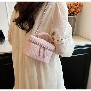 Detailed view of pink quilted leather cosmetic bag with silver chain strap and top handle