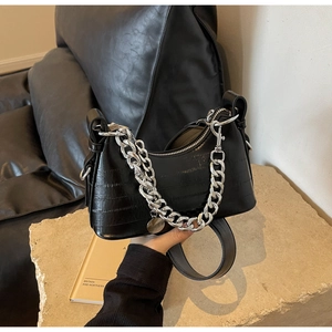 Detail of black crocodile pattern handbag with silver chain and glossy leather finish