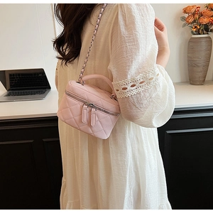 Detail of pink quilted mini crossbody bag with double zippers and chain strap