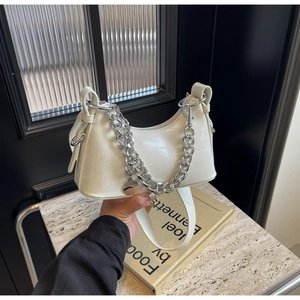 Detail of white crocodile pattern underarm bag with thick silver metal chain and zipper