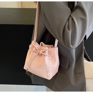 Détail du sac seau en cuir rose clair avec un nœud coulissant et des embouts métalliques