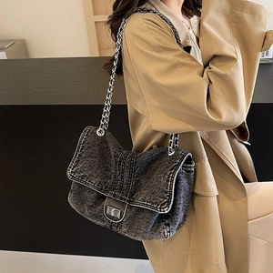 Detail of vintage washed black denim shoulder bag with silver chain and turn-lock