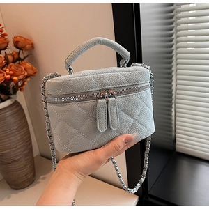 Detail of light blue quilted leather bag with silver chain strap and top handle design