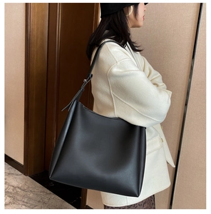 Detail of adjustable metal buckle on shoulder strap of large black matte leather tote