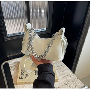 Close-up of white crocodile embossed half-moon bag with chunky silver chain link