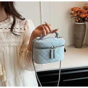 Detail of light blue quilted mini bag with silver double zippers and elegant chain strap