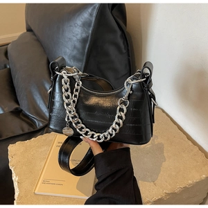 Detail of black textured PU leather underarm bag with thick silver chain and metal charm