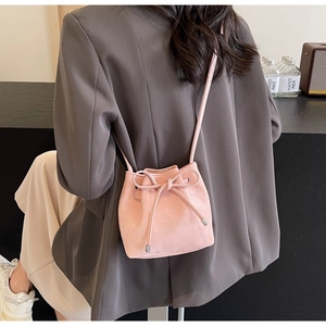 Sac seau rose à cordon avec nœud et fine bandoulière sur une veste de blazer grise