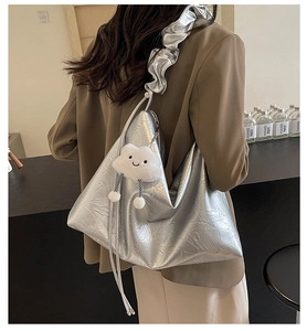 Metallic silver tote bag with ruffled strap and plush cloud charm shown on model