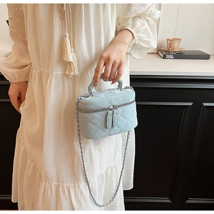 Detail of light blue quilted mini vanity case with chain strap and leather handle