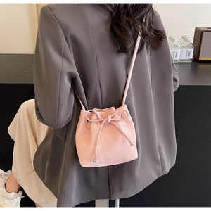 Sac seau rose à cordon avec nœud papillon porté par un mannequin dans un décor moderne