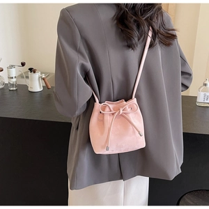 Sac seau rose avec détail de nœud et cordon de serrage porté en bandoulière