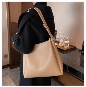 Detail of adjustable shoulder strap and smooth leather texture on soft beige tote bag