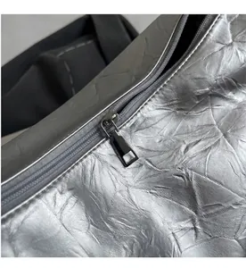 Close-up of smooth metal zipper and silver crinkled texture on minimalist tote bag