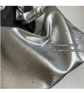 Detail of silver tote bag showing glossy metallic crinkled texture and soft fabric material