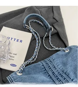 Détail d'un sac en denim bleu avec bandoulière en chaîne argentée et surpiqûres