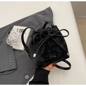 Gros plan du sac seau noir avec texture vintage et détail de nœud en cuir élégant