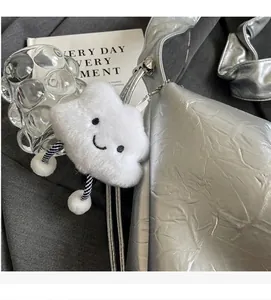 Close-up of cloud plush charm with striped legs hanging on a silver tote bag