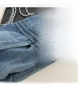 Détail du sac cabas en denim bleu avec fermoir tournant en métal et bandoulière
