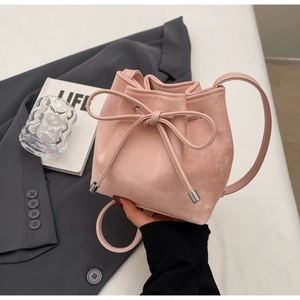 Détails d'un sac seau rose à cordon avec texture suédée et embouts métalliques