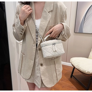 Detailed view of white quilted mini box bag with chain strap worn by a model