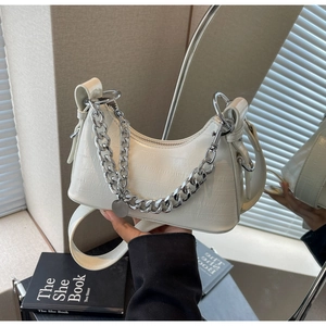 Detail of cream white faux leather underarm bag with crocodile pattern and silver chain