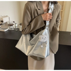 Detail of silver metallic tote bag with crinkled texture and white cloud plush charm