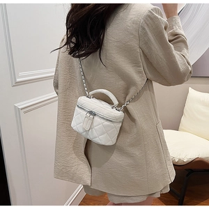 Rear view of model carrying a white quilted leather vanity case bag with chain strap