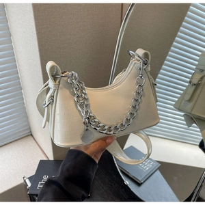 Detail of white crocodile pattern underarm bag with silver chain and metal tag