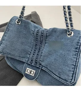 Détail du sac en denim bleu avec bandoulière chaîne et surpiqûres matelassées